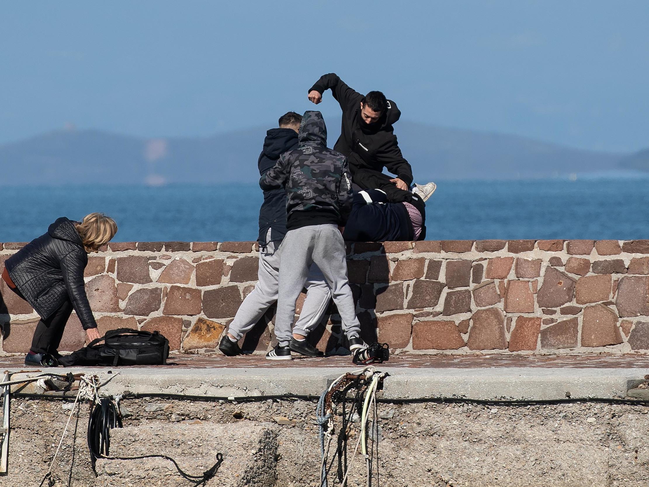 Locals attack journalists and try to stop migrants disembarking on Greek island