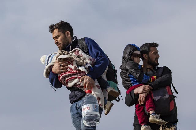 Refugees holding small infants walk towards the Turkish-Greek border on 3 March 2020