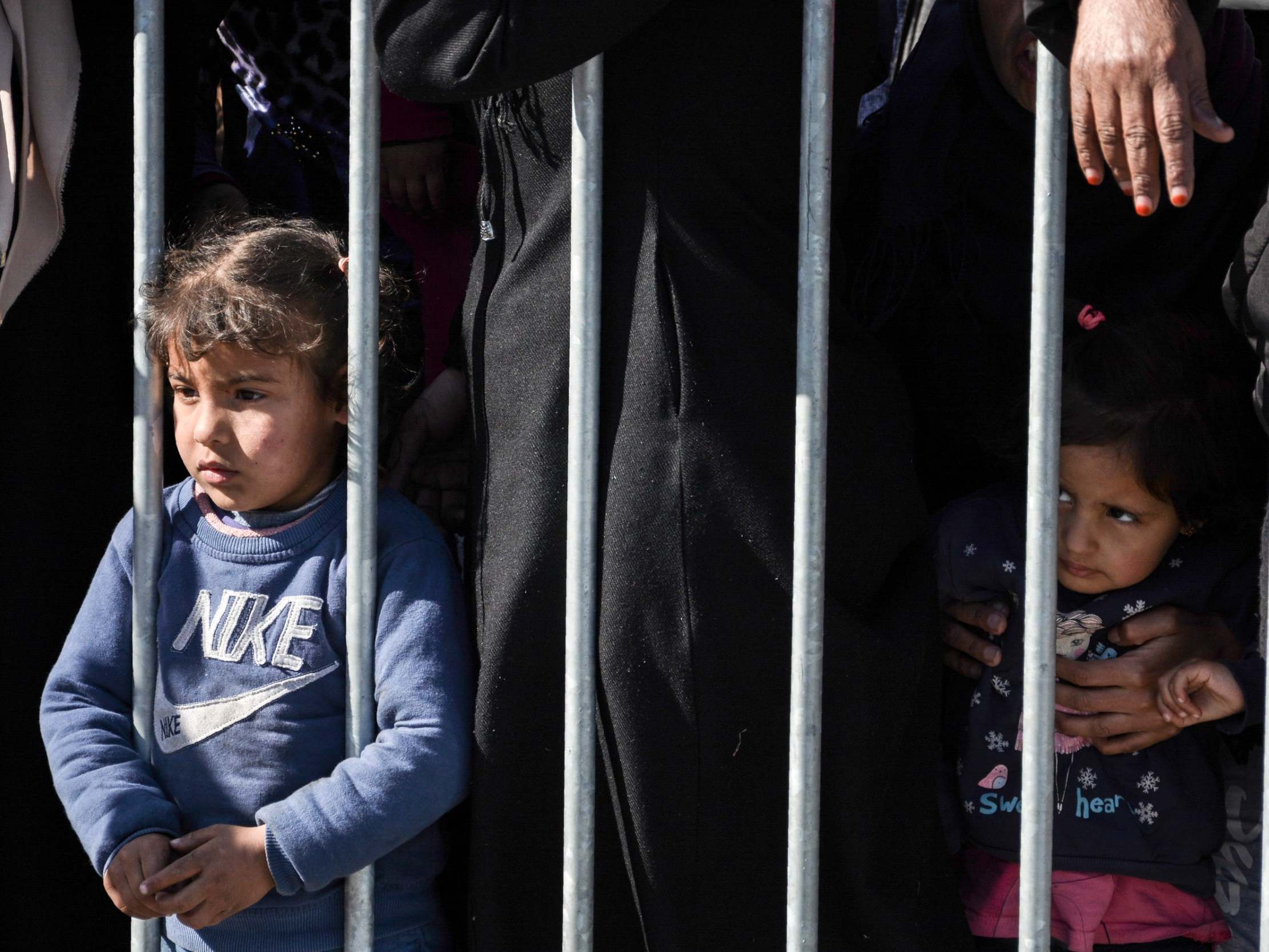 Migrants and their children wait in line for food and water distribution at the port of Mytilene, on the northeastern Aegean island of Lesbos