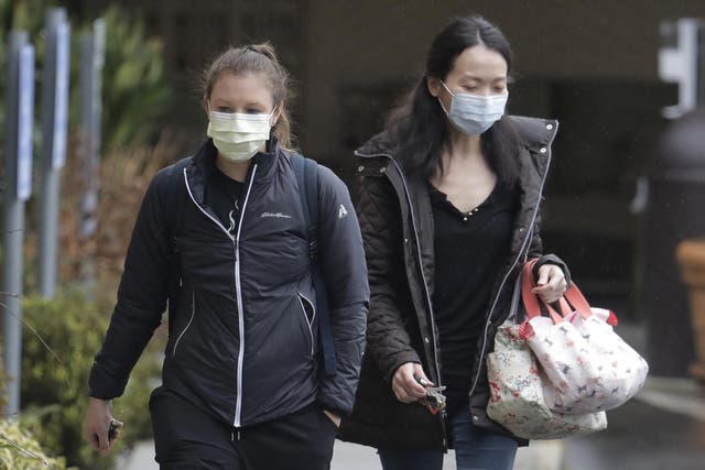Two women wearing masks walk away from the Life Care Center in Kirkland, near Seattle, Washington, where there have been a number of deaths from coronavirus.