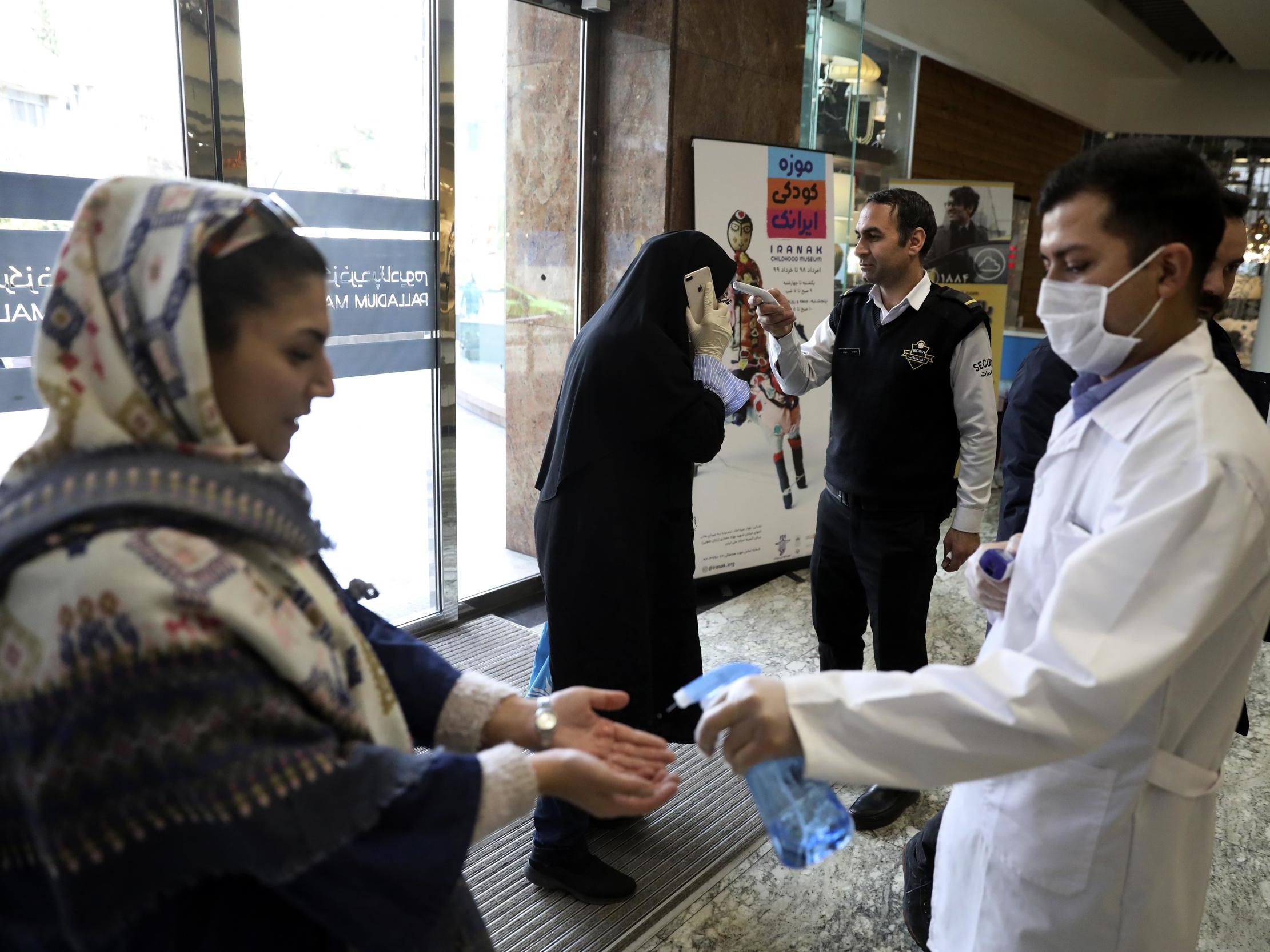 People have their temperature checked and their hands disinfected as they enter the Palladium Shopping Center, in northern Tehran, Iran