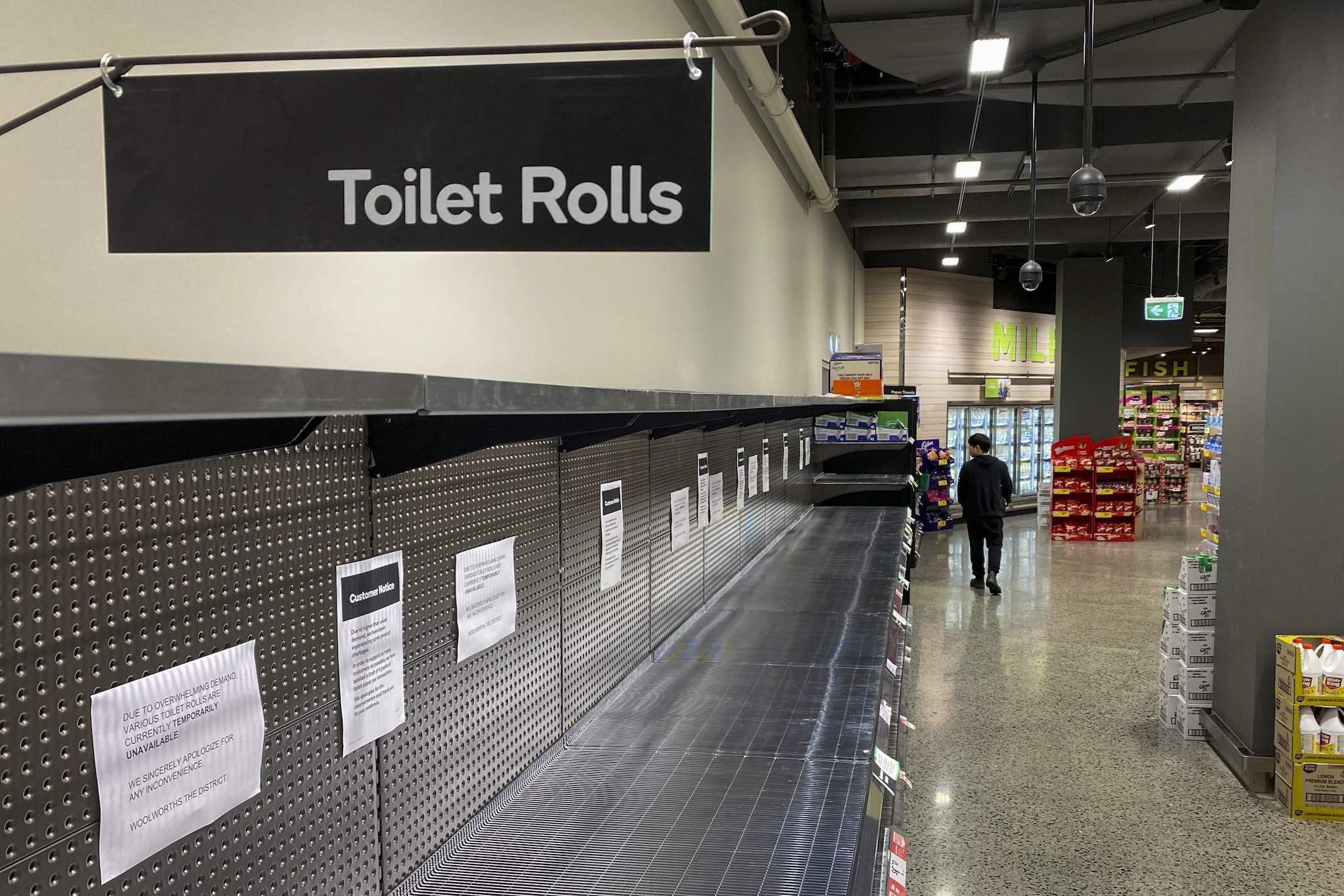 A shopper passes empty shelves usually stocked with toilet paper in a supermarket in Melbourne on March 5, 2020