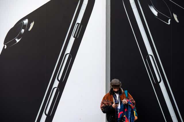 A man checks his phone next to billboards advertising the an Apple iPhone 7 smartphone as he stands on Oxford Street in London on March 7, 2017