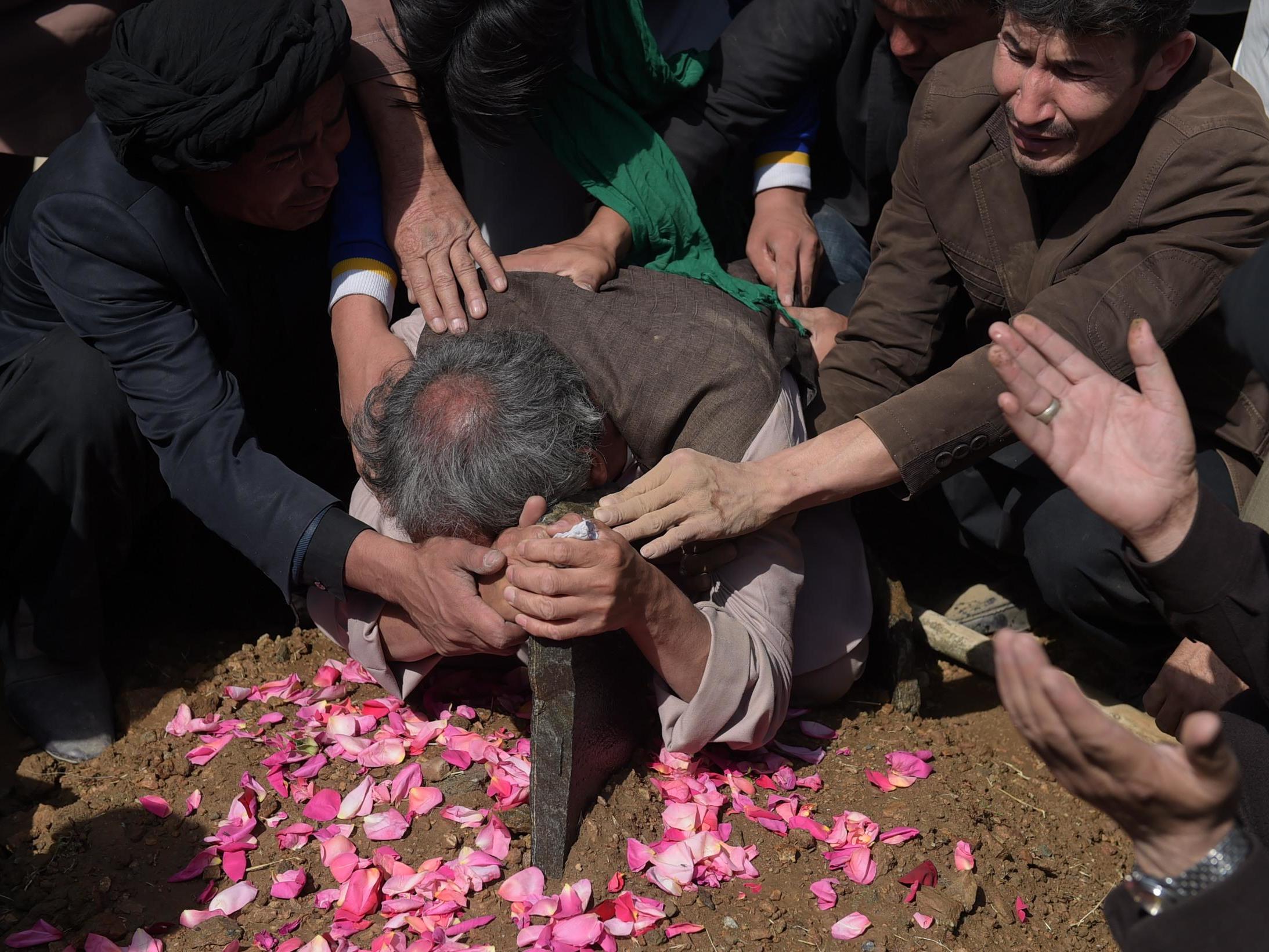 An elderly father mourns at the grave of his son in Kabul after he was killed in an attack by gunmen
