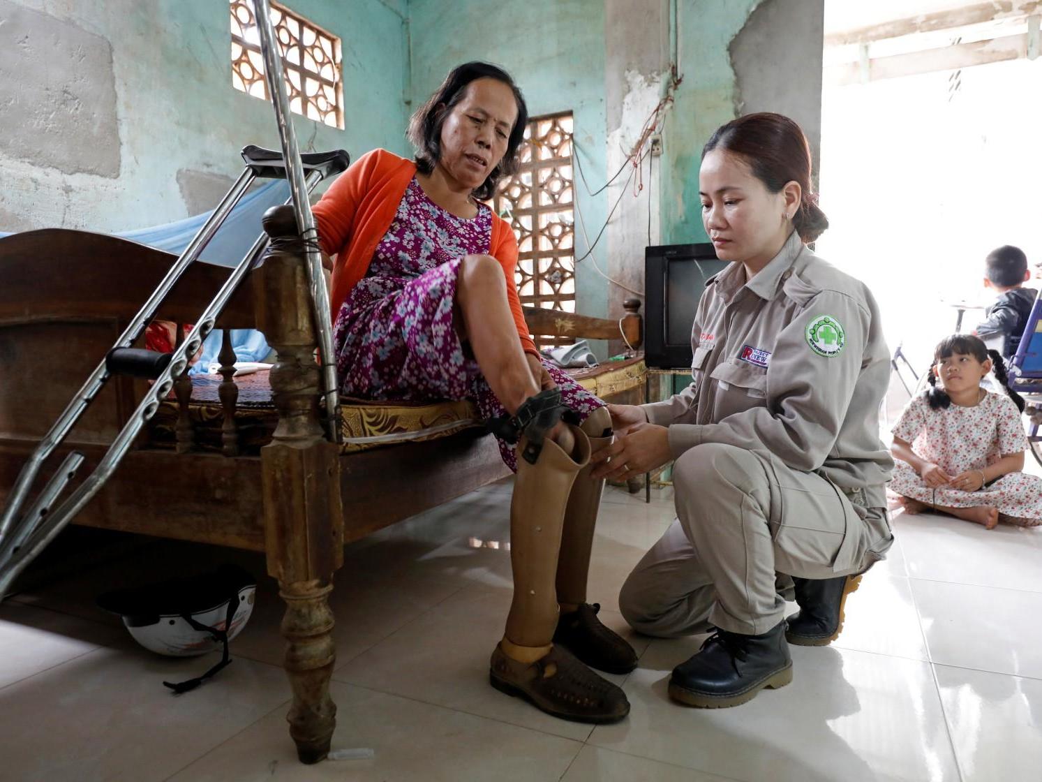 Hoang Thi Hoa, who lost both legs and an arm due to unexploded ordnance during the Vietnam War, is assisted by her daughter Nguyen Thi Ha Lan at their house in Quang Tri province, Vietnam on 4 March 2020