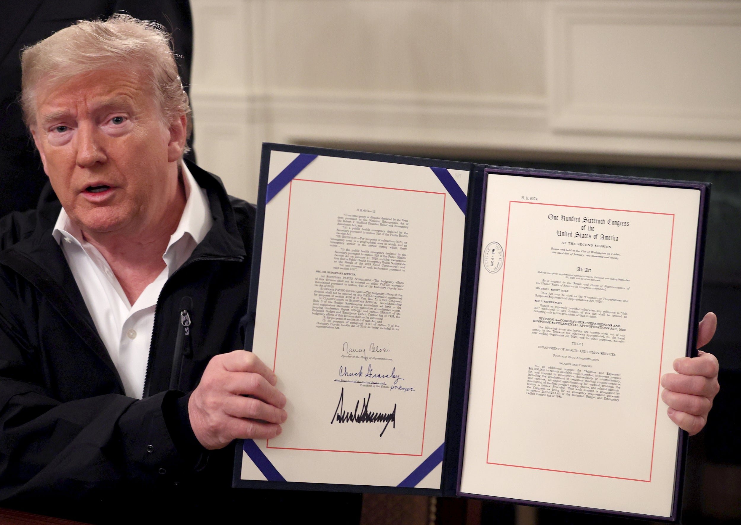 Trump shows off a bipartisan $8bn funding bill he signed to combat the coronavirus outbreak (Getty)