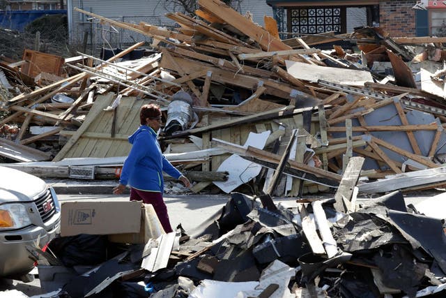 A woman walks down a street lined with debris in Nashville after tornadoes hit the state