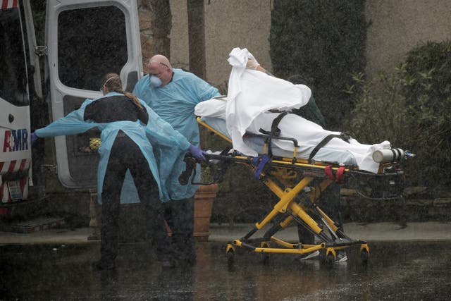 Medics transport a patient through heavy rain into an ambulance at Life Care Center of Kirkland, the long-term care facility linked to several confirmed coronavirus cases in the state, in Kirkland, Washington