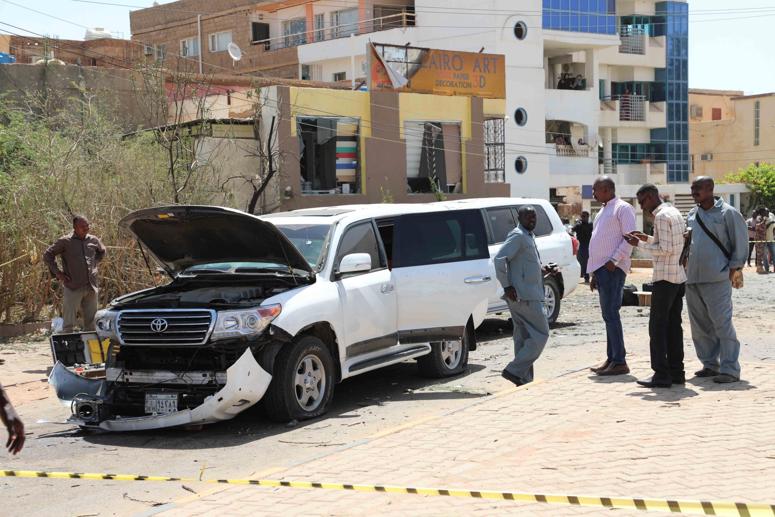 Sudanese police officers assess the damage after an explosion went off near the Sudanese prime minister's convoy