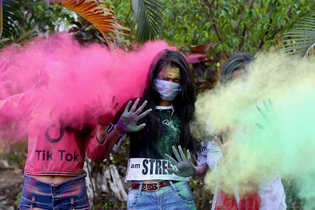 People play with coloured powder as they wear protective masks during Holi festival celebrations in Bhopal on Monday