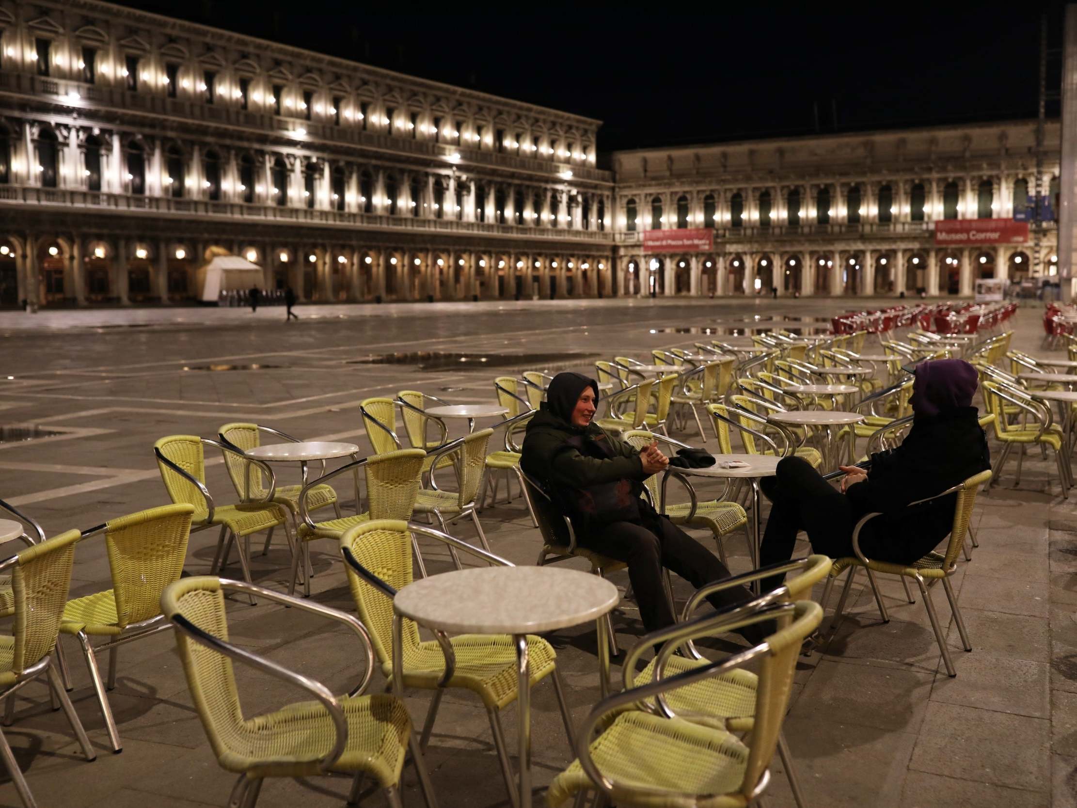 Two foreign tourists talk in a deserted San Marco Square, Venice, after Italy's prime minister announced a national emergency due to coronavirus