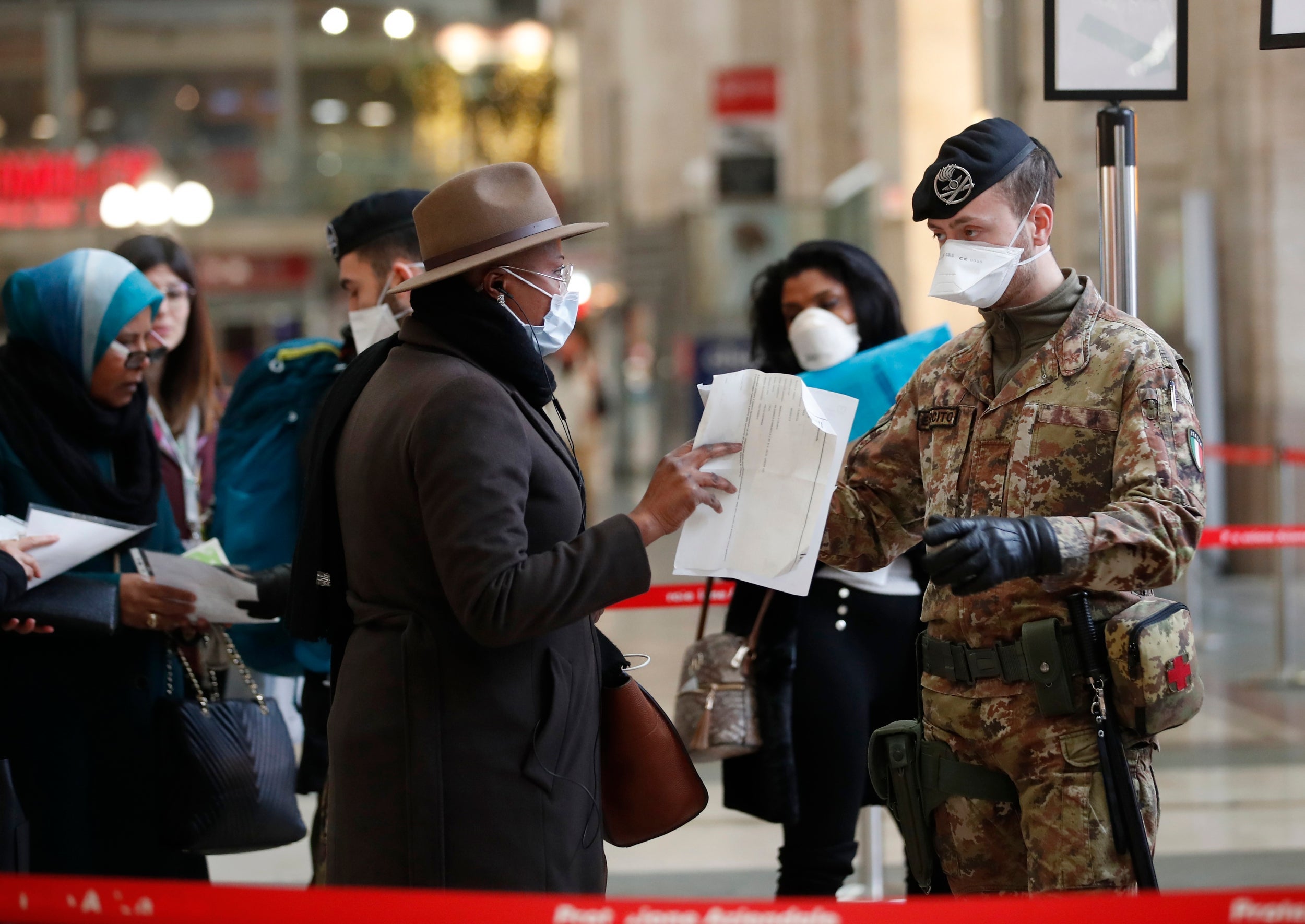 Police officers and soldiers check passengers leaving from Milan’s main train station