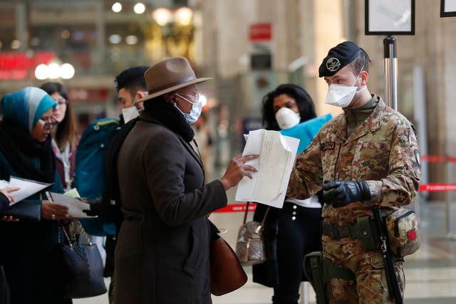 Police officers and soldiers check passengers leaving from Milan’s main train station