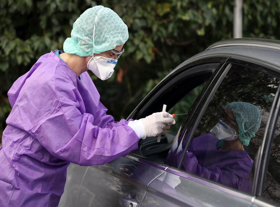 Dr. Roxana Sauer, dressed in a protective suit, demonstrates the procedure of taking a nasal swab from a visitor in his car to test for possible coronavirus infection at the Kreissklinik Gross Gerau regional clinic on March 9, 2020 in Gross Gerau, Germany