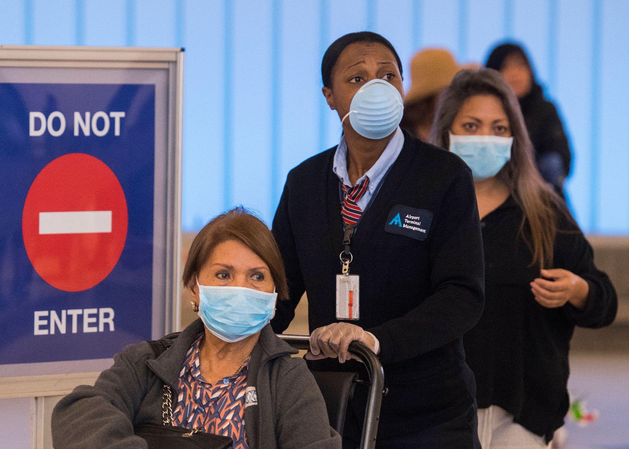 Passengers wear face masks to protect against the COVID-19 (Coronavirus) after arriving at the LAX airport in Los Angeles, California on March 5, 2020