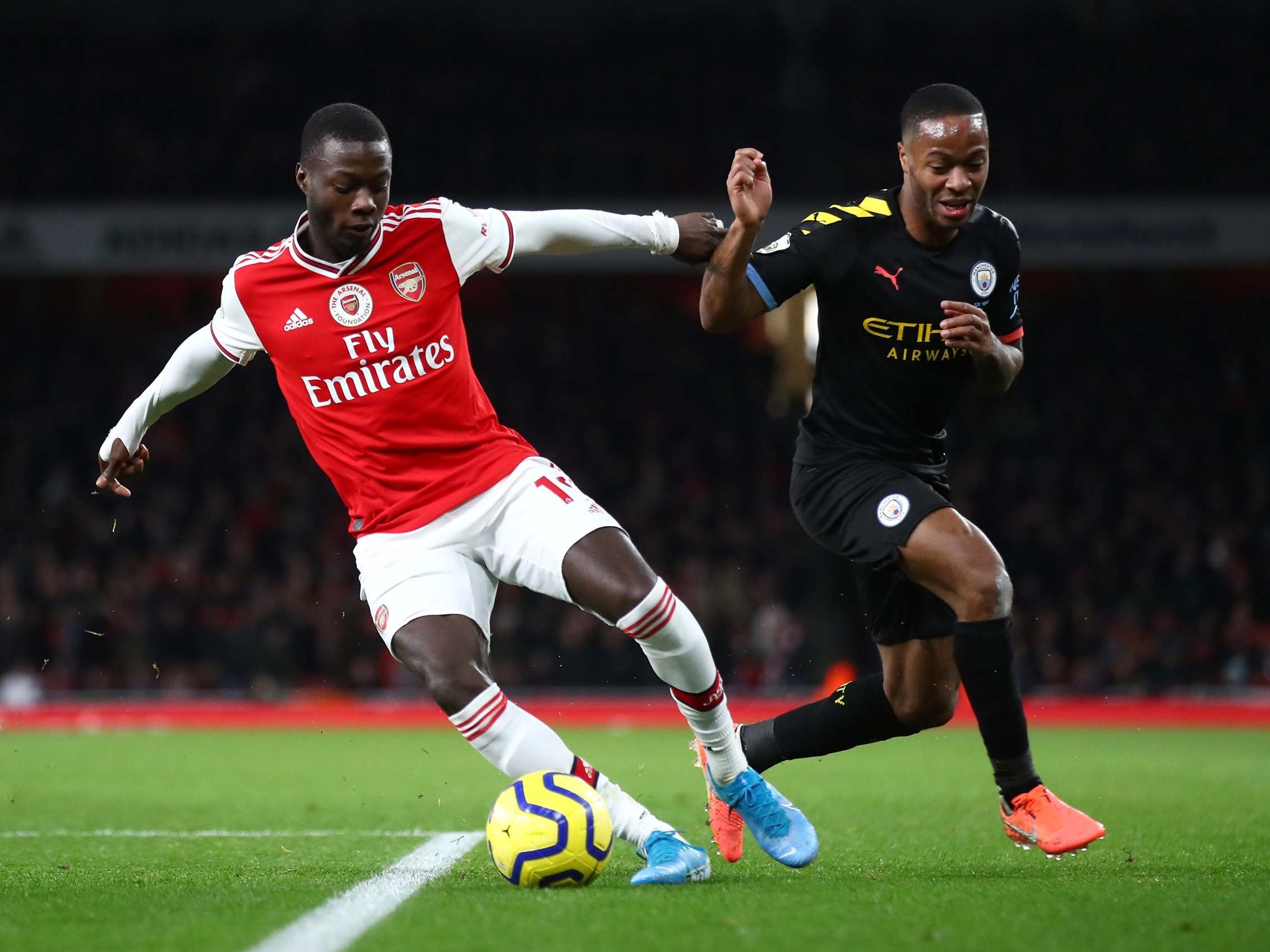 Nicolas Pepe of Arsenal is challenged by Raheem Sterling of Manchester City