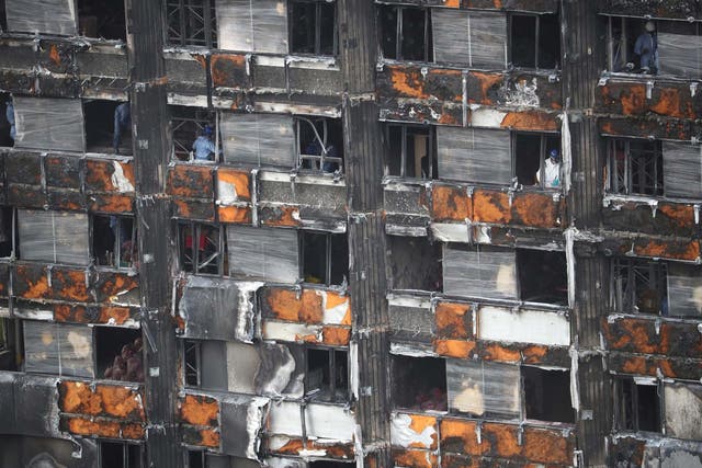 Workers stand inside the burnt out remains of the Grenfell Tower
