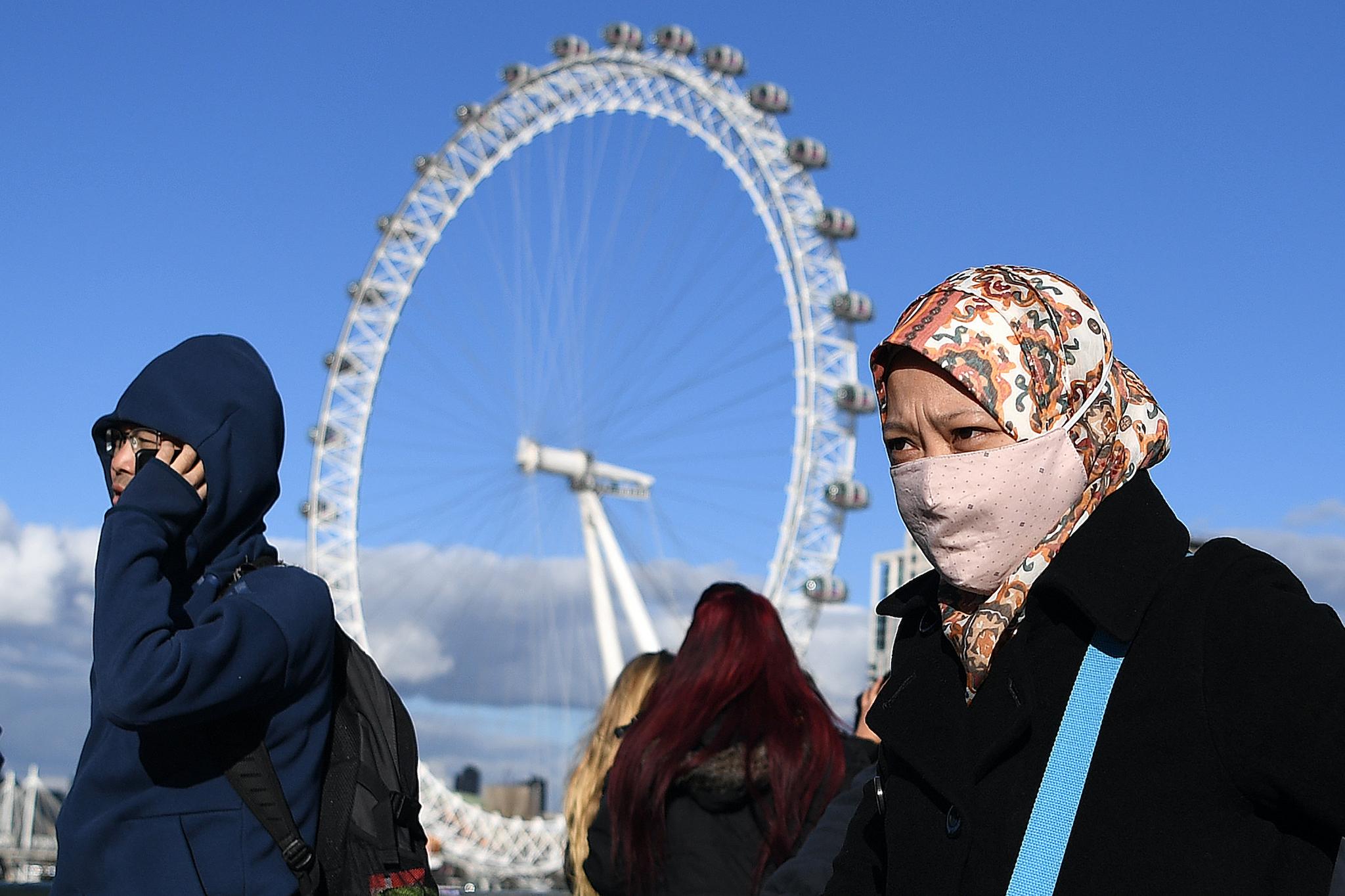 A woman wearing a face mask walks across Westminster Bridge, near the London Eye landmark in central London on March 2, 2020