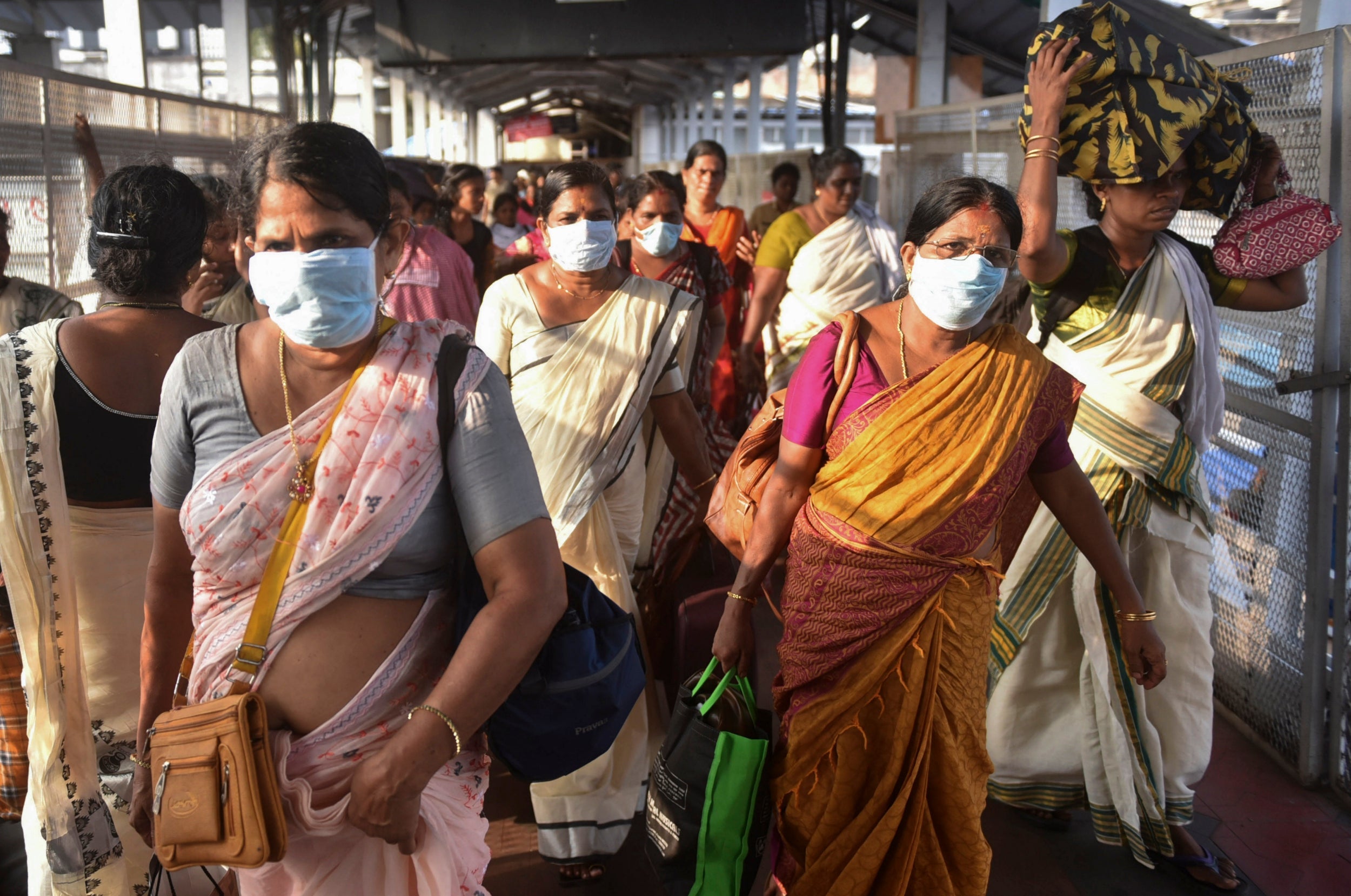 Indian women wear masks as a precaution against coronavirus as they leave the Attukal temple in Thiruvananthapuram, Kerala