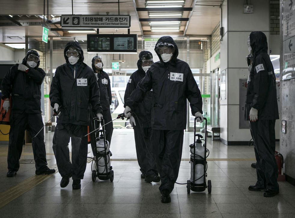 Members of the reserve forces, wearing protective gear, spray antiseptic solution to guard against the coronavirus (COVID-19) at the metro station on March 12, 2020, in Seoul, South Korea