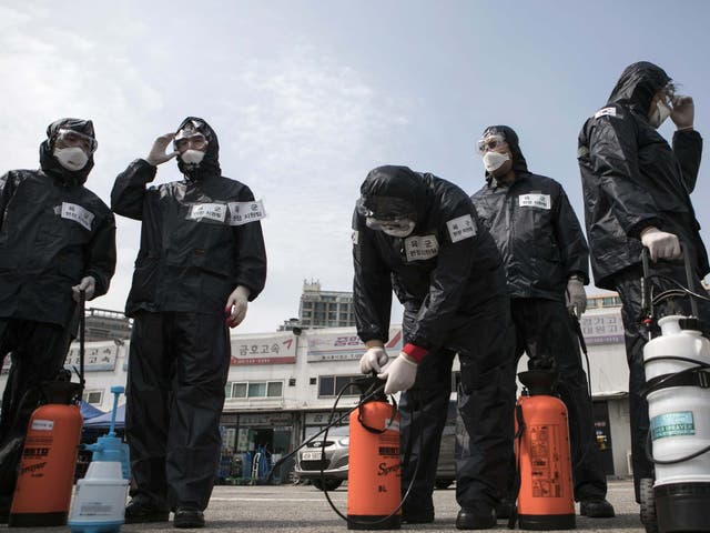 Members of South Korea's reserve forces wearing protective gear prepare to spray antiseptic solution to guard against coronavirus. The country is testing 20,000 people a day in a huge effort to control the outbreak