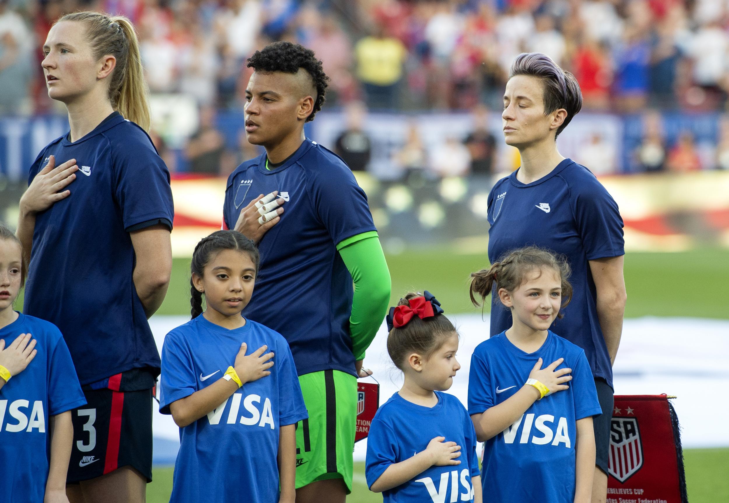 US women's national team players, including Megan Rapinoe (right) stand with their jerseys turned inside out during the playing of the national anthem before a SheBelieves Cup women's soccer match against Japan