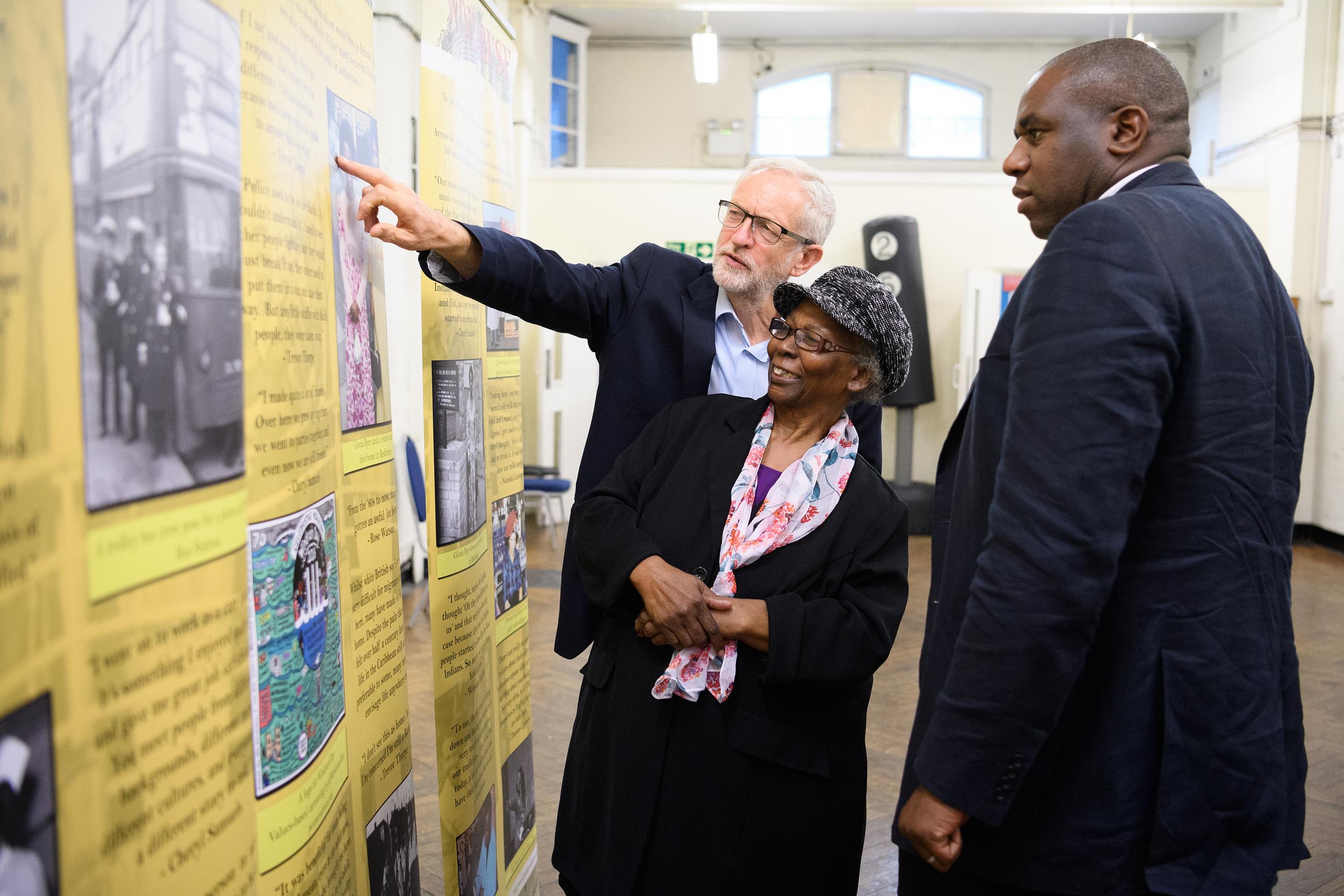 Jeremy Corbyn and David Lammy with Windrush migrant Gloria Byer as they look at an exhibition on the subject