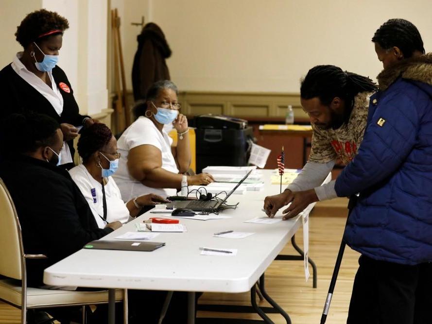 Election workers wear protective face masks as they check voters to get their to vote in the Michigan primary election at Central United Methodist Church in Detroit, Michigan, on 10 March 2020.