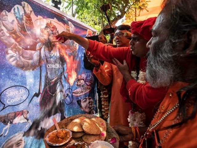 Members of All India Hindu Mahasabha offer cow urine to a caricature of the coronavirus as they attend a gaumutra (cow urine) party, which according to them helps in warding off coronavirus disease (COVID-19), in New Delhi, India March 14 2020