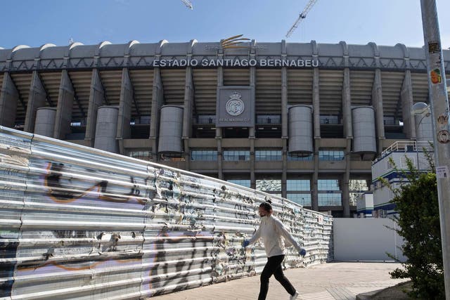 A woman wearing a protective mask walks past Real Madrid's Santiago Bernabeu stadium