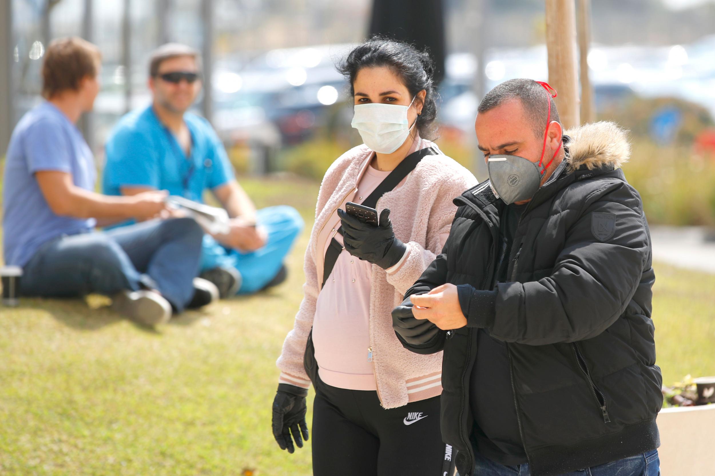 People wearing protective masks walk in the southern Israeli city of Ashdod, as the Jewish state introduces stringent measures to control the coronavirus pandemic