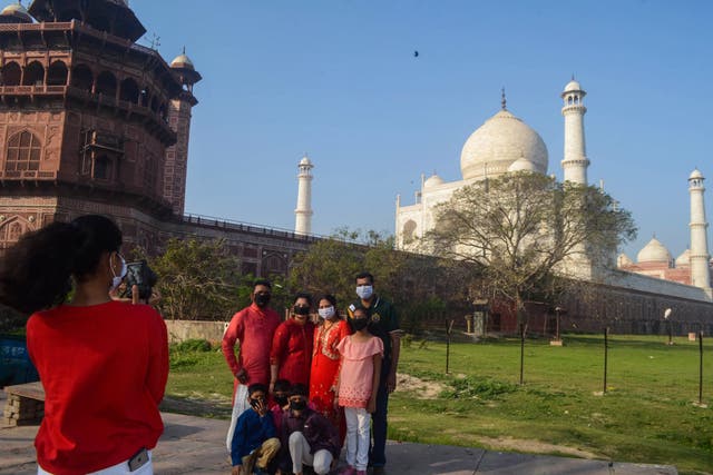 Visitors wearing face masks take pictures outside the Taj Mahal following its closure on Tuesday