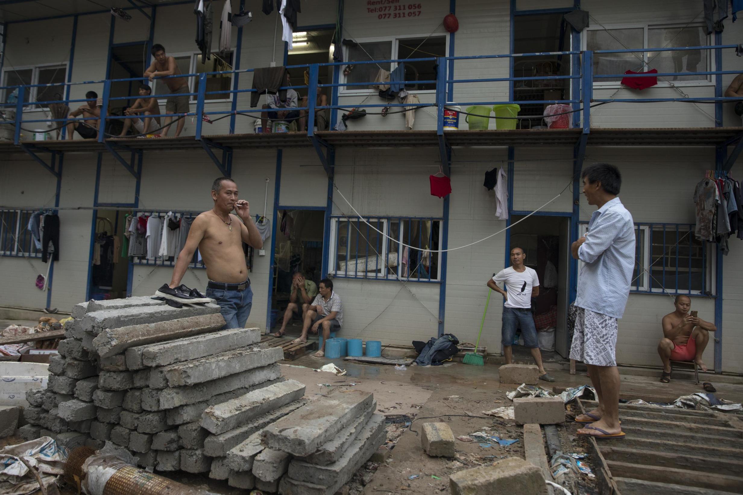 Chinese workers relax in a cramped housing complex next to the massive Blue Bay Beach Resort construction site (Getty)