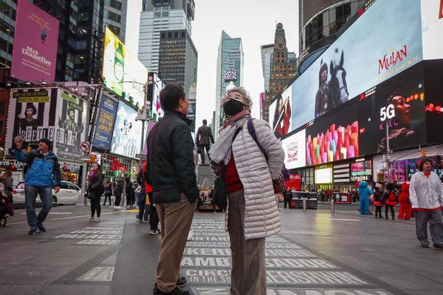 A pedestrian wearing a face mask stops in Times Square, Thursday, March 12, 2020, in New York.