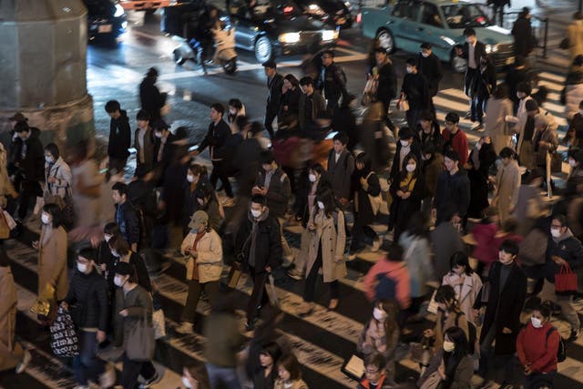 Pedestrians wearing face masks cross a road on March 14, 2020 in Osaka, Japan