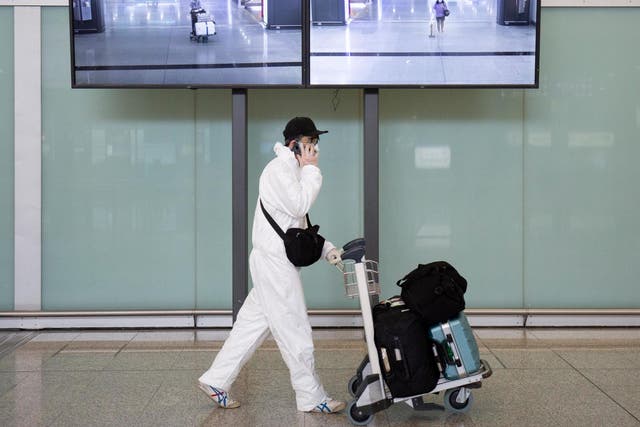 A passenger wearing protective gear, as a precautionary measure against coronavirus, walks in the arrivals area after landing at the Hong Kong International Airport