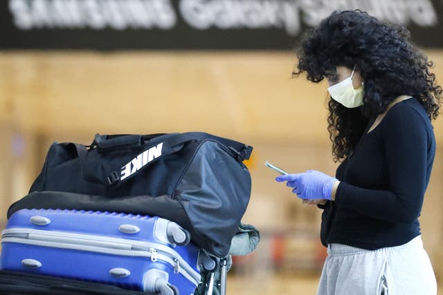 A passenger wearing a protective masks checks her phone at the arrival hall of Ben Gurion International Airport near Tel Aviv, on March 10, 2020 amid major restrictions on travellers from several countries