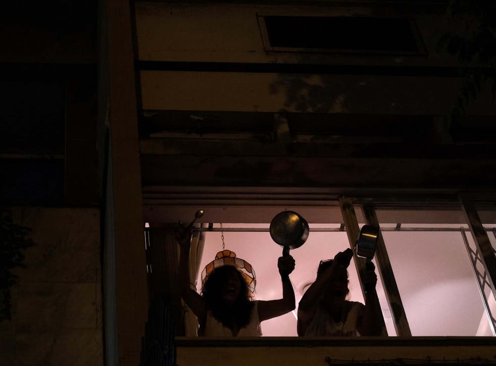 Women bang pots at the window of their house as they protest against Brazilian President Jair Bolsonaro during the coronavirus disease (COVID-19) outbreak in Rio de Janeiro