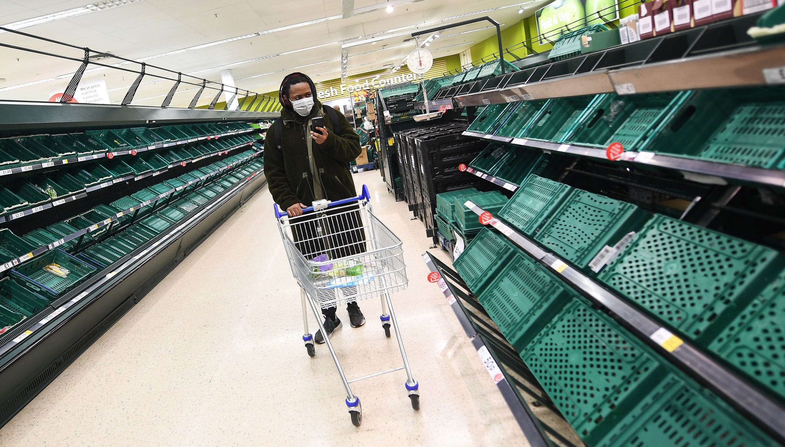 A shopper passes empty shelves at a supermarket in London