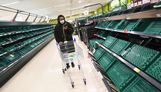 A shopper passes empty shelves at a supermarket in London