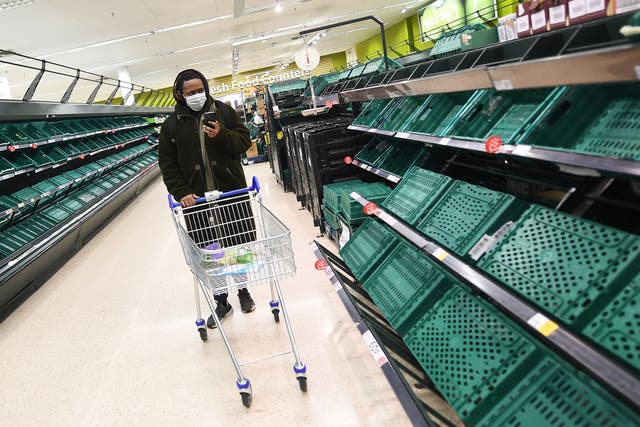 A shopper passes empty shelves at a supermarket in London