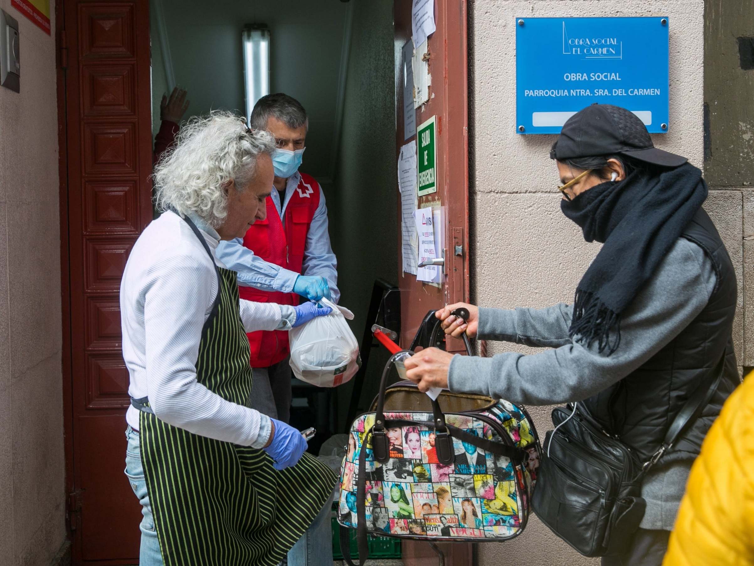 Volunteers from a parish give away bag with food to people in need in Zaragoza, Spain
