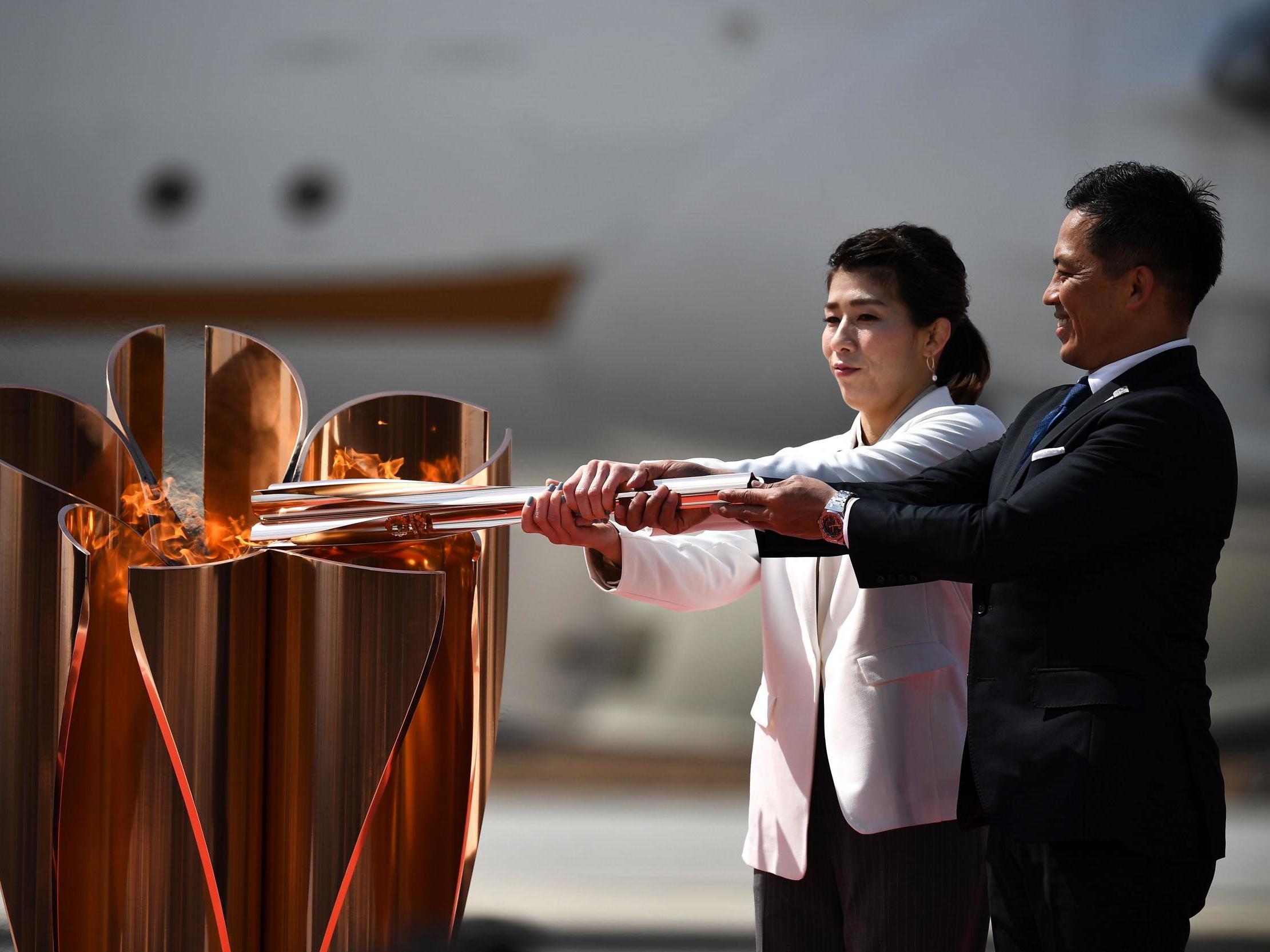 Saori Yoshida (L) and Tadahiro Nomura (R) light a Tokyo 2020 Olympic cauldron with the Olympic flame