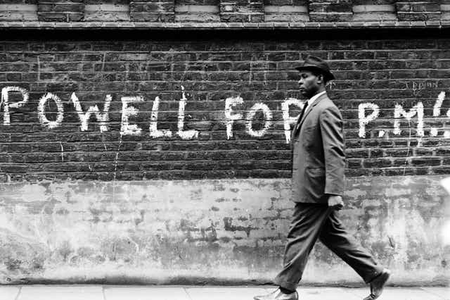 A man walks past graffiti referring to Enoch Powell, known for his opposition to immigration and racial integration, in 1968