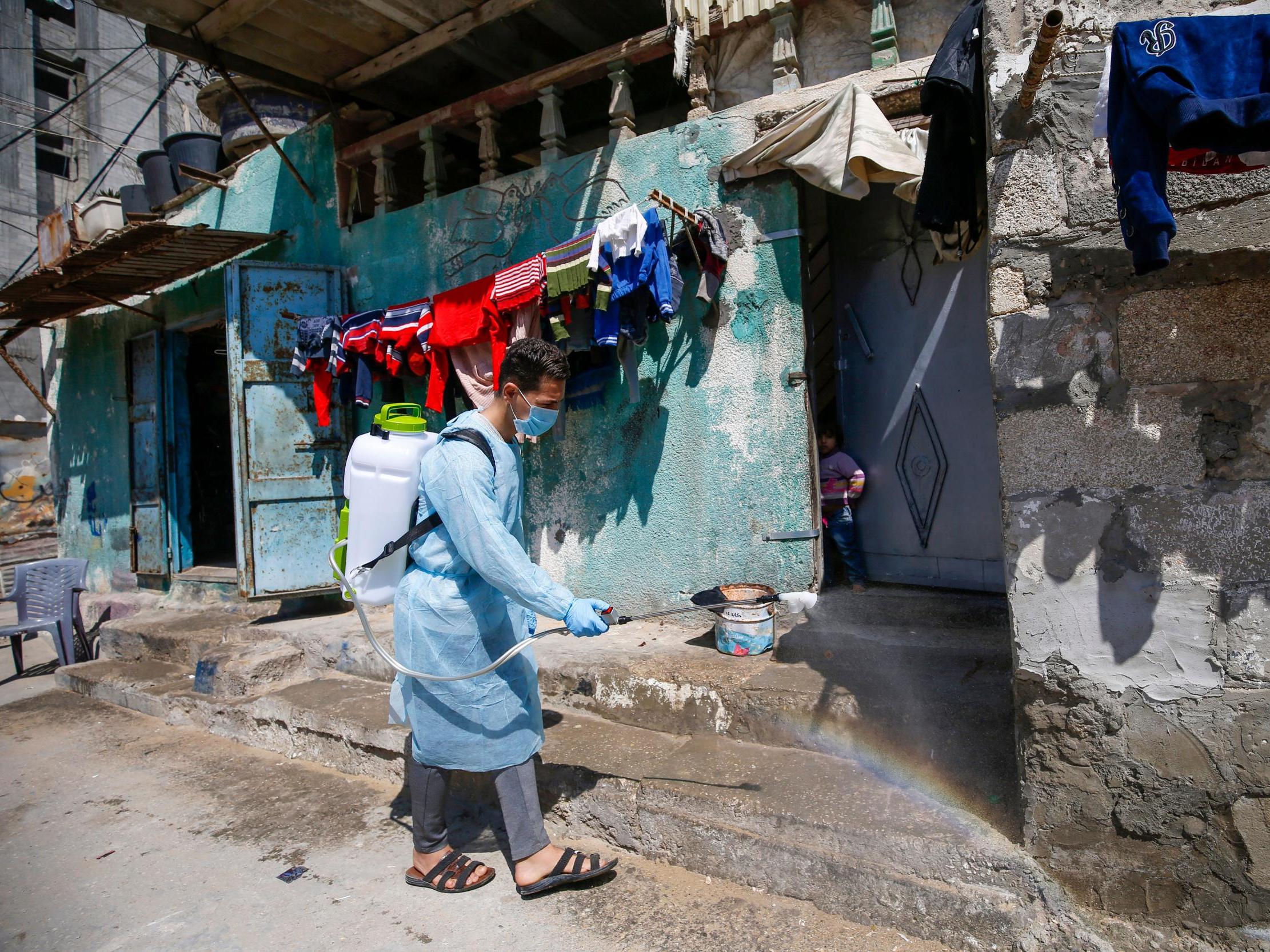 Palestinian volunteers spray disinfectant on a street at al-Shati refugee camp in Gaza City