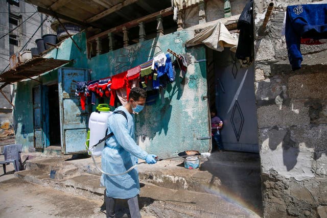 Palestinian volunteers spray disinfectant on a street at al-Shati refugee camp in Gaza City