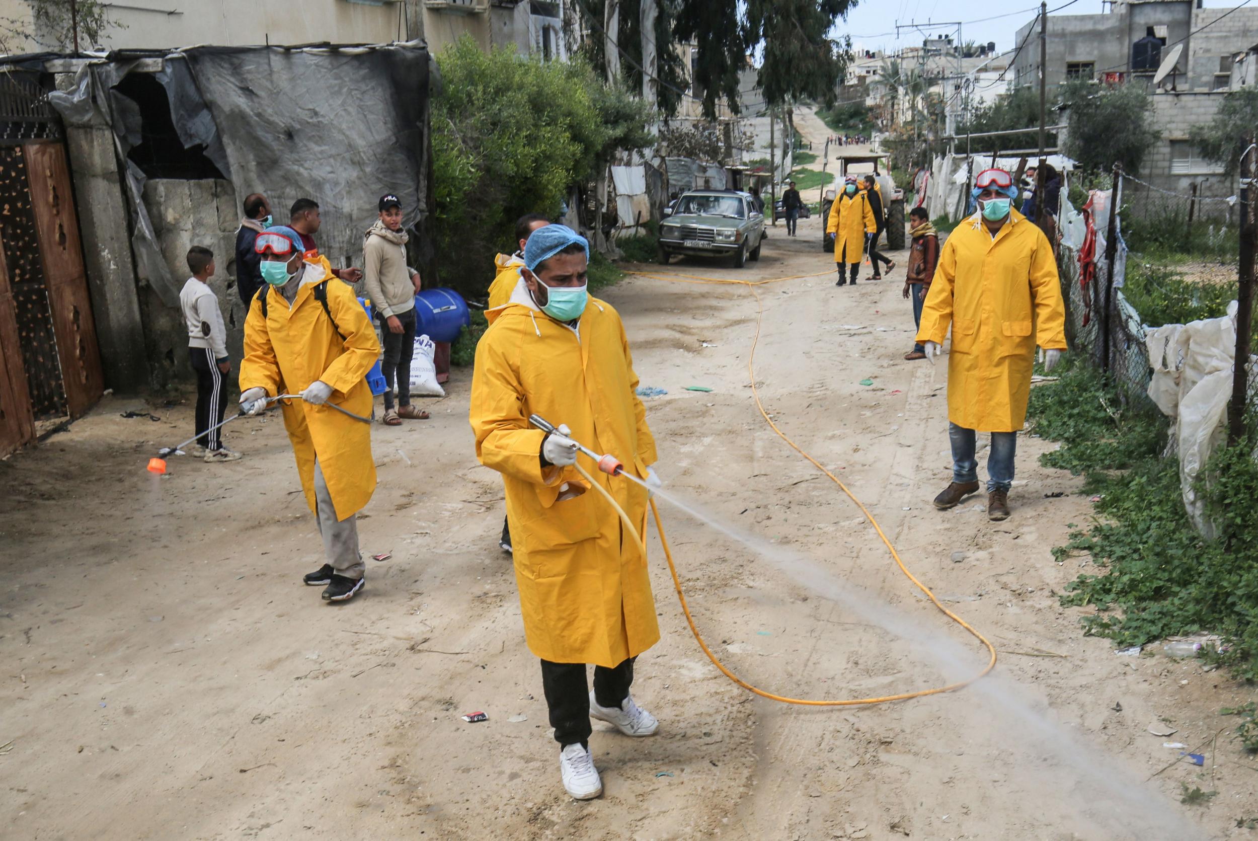 Palestinian volunteers wearing protective clothes and masks disinfect a street as a preventive measure against the spread of the novel coronavirus, in Rafah (AFP/Getty)