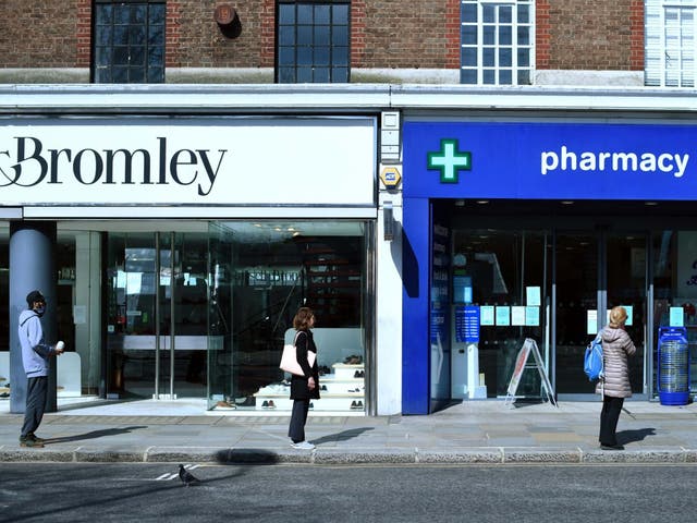 Customers queue up two metres apart for a pharmacy in London during the nationwide lockdown