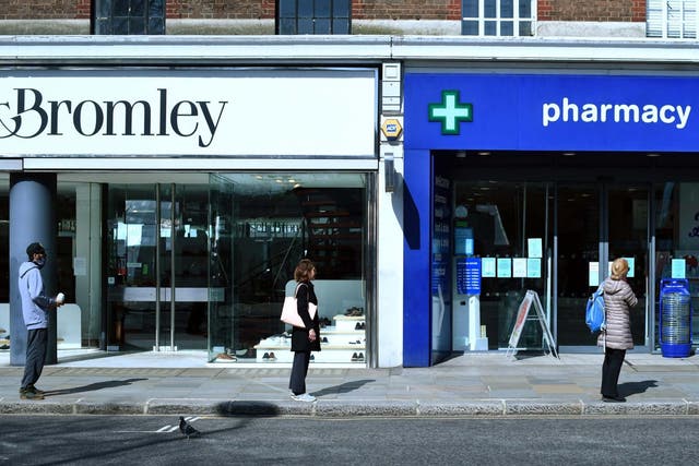 Customers queue up two metres apart for a pharmacy in London during the nationwide lockdown