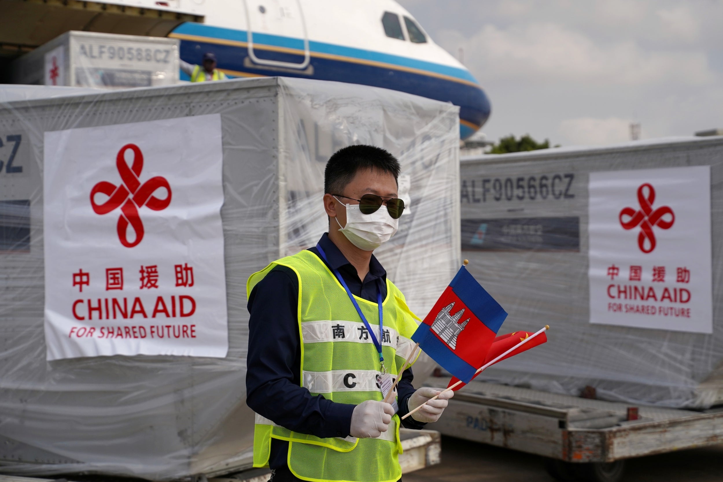 A Phnom Penh airport worker waits as a Chinese plane arrives with medical workers and supplies